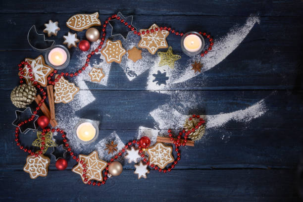 istock Falling star shape from icing sugar,  Christmas decoration, gingerbread cookies  and burning candles on a dark blue wooden background, high angle view from above 1194166899