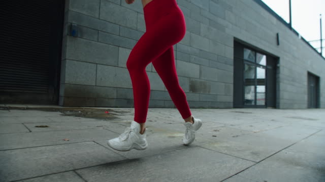 Girl legs running outdoor in slow motion. Close up female legs running on street