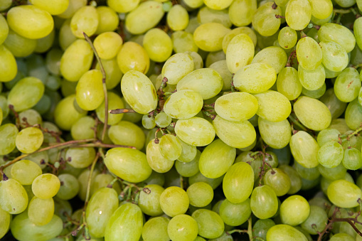 green grapes racemation background at farmer's market shelves close-up.