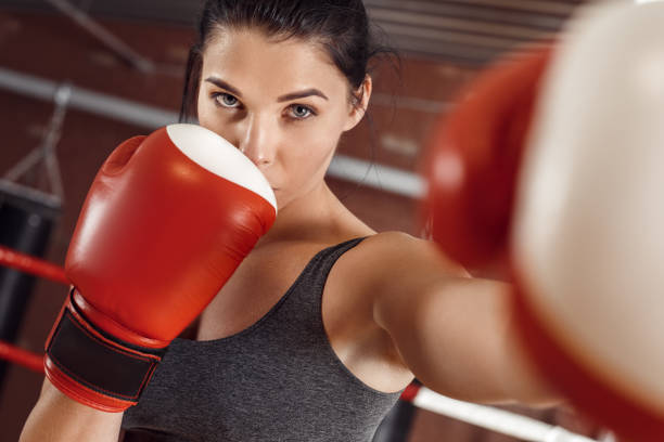istock Boxing. Woman boxer in gloves practicing hit on ring close-up 1194177695