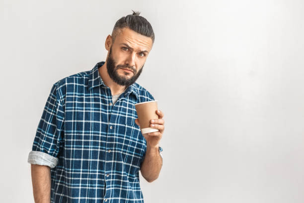 istock Freestyle. Guy in checkered shirt standing isolated on white drinking hot coffee looking amera curious copy space 1194177746