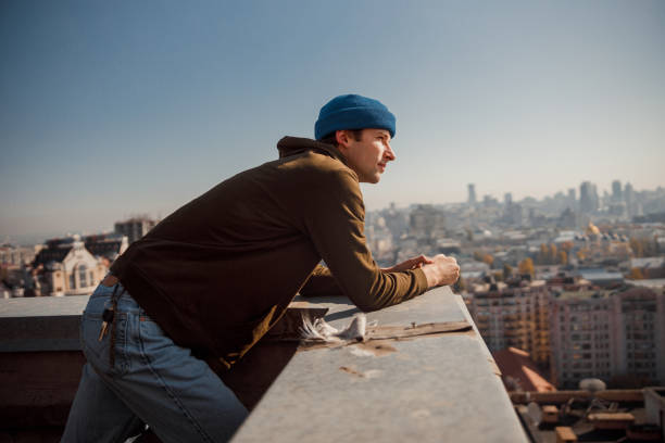 Side view of young male resting on rooftop stock photo