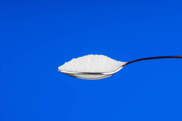 istock Spoon with white sugar on a blue background 1194182767