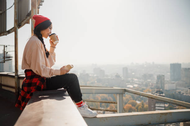 istock Smiling young girl drinking coffee on roof 1194184849