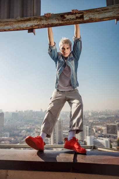 istock Stylish guy in red sneakers standing on the roof 1194184894