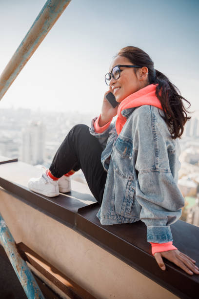 istock Happy pretty lady talking on smartphone on roof 1194186193