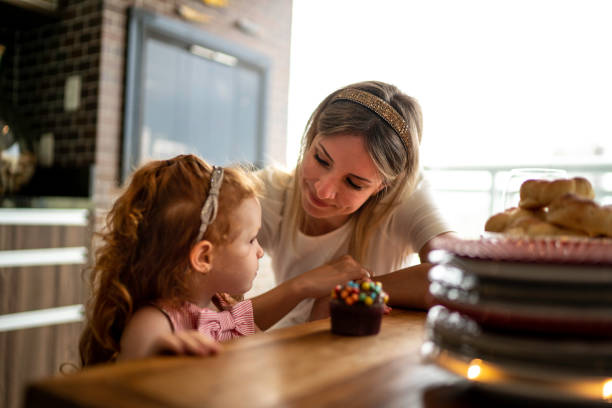 istock Daughter and mother eating cupcake at table 1194186251