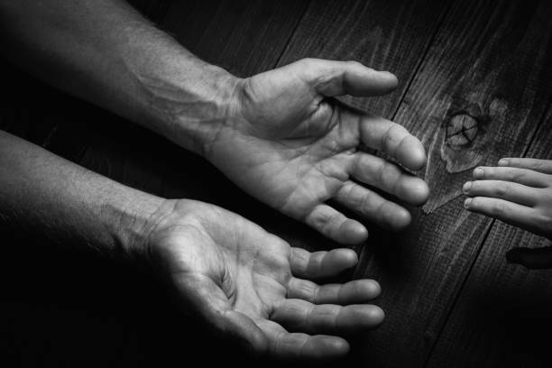 istock Adult hands holding kid hands, black and white. 1194187098