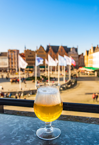 Golden beers in a cafe with view of Bruges in Belgium with 13th Century shops and restaurants lining the square