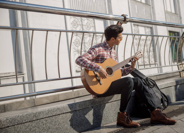 istock Young guy picking up guitar chords outdoors 1194188049
