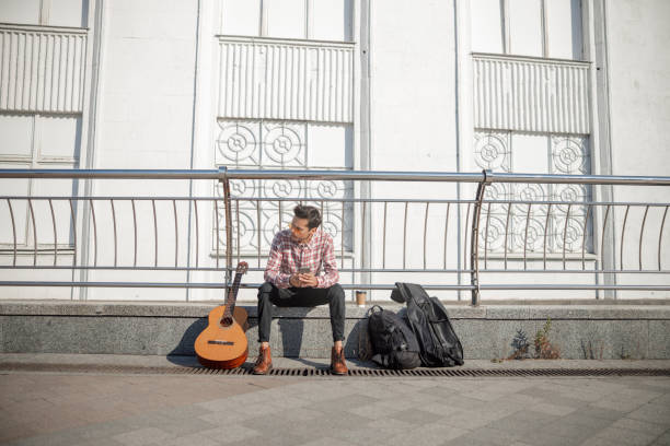 istock Young guy with guitar is looking away outdoors 1194188085