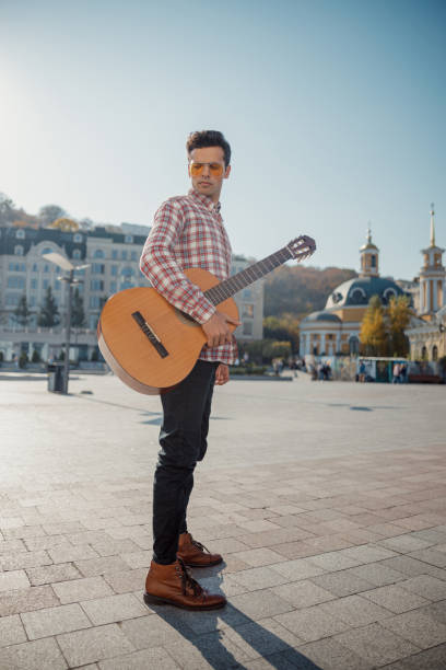 istock Musician with a guitar standing in the square 1194188117