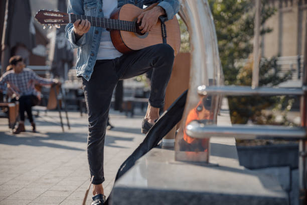 istock Young guy holding guitar and playing on the street 1194190583