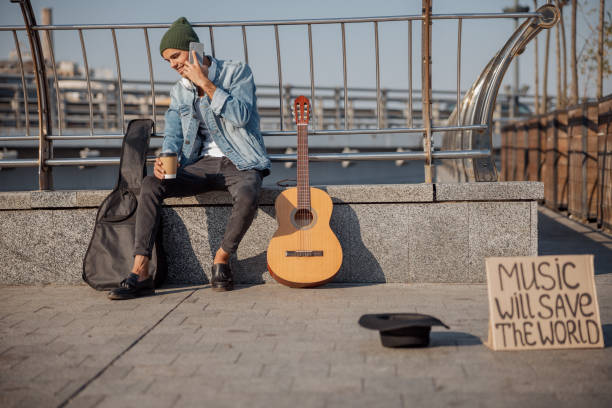 istock Smiling guy with guitar using smartphone on the street 1194190596