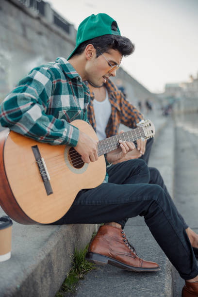 istock Young guy playing guitar on steps outdoors 1194190648