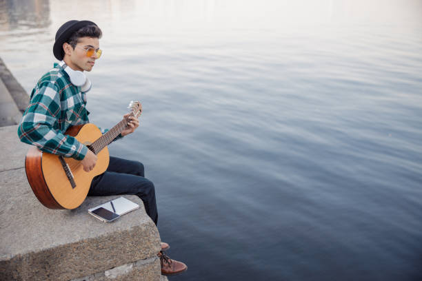 istock Young guitarist looking away while playing guitar 1194190665