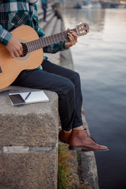 istock Guitarist sitting with notebook and smartphone outdoors 1194190667