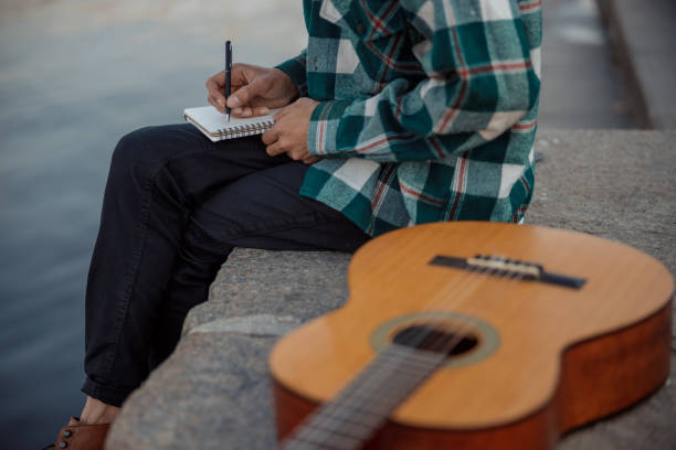istock Young guy with guitar sitting near river 1194190673