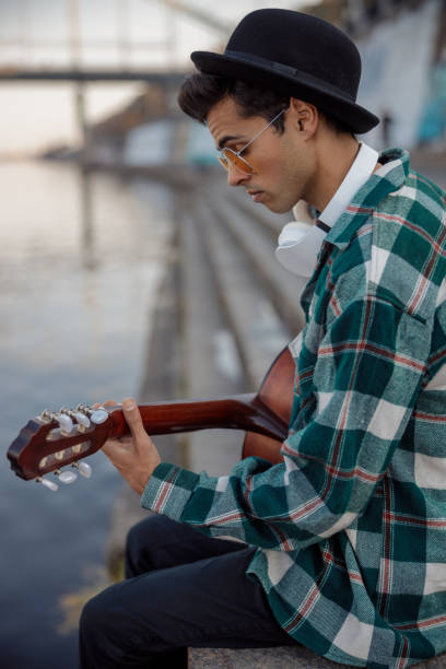 istock Stylish guy with headphones looking at guitar 1194190674
