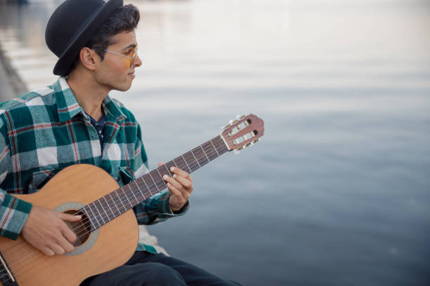 istock Smiling guy with guitar sitting near river 1194191694