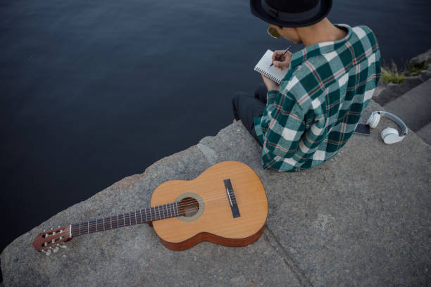 istock Guitarist is writing on notebook near river 1194191698
