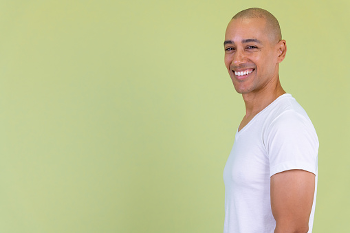 Studio shot of handsome bald man with mixed race against colored background