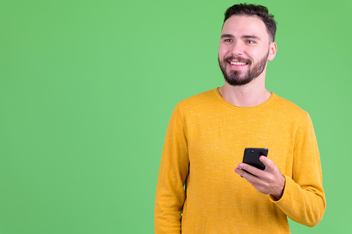 Studio shot of young handsome bearded man against chroma key with green background