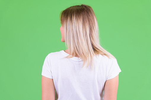 Studio shot of young beautiful woman with blond hair against chroma key with green background