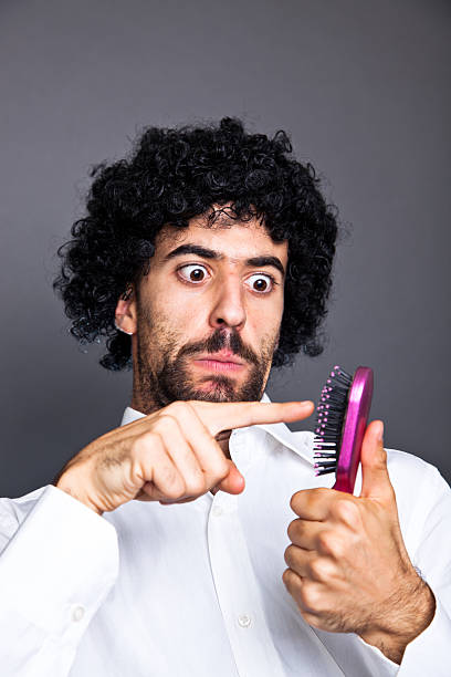 istock Young Doubtful Man with Wig Look an Hairbrush 119421006