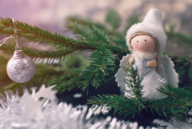 istock Black festive background with contrasting white and green objects - a natural green spruce branch, white snowflakes, silver shiny Christmas toys and a white angel with wings 1194212964