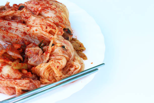 istock Traditional Korean cabbage kimchi on white plate and chopsticks, white background. 1194219995