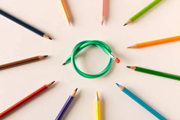 Colored pencils with one flexible pencil on white background. The concept of flexibility in decision-making