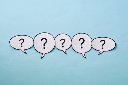 Line of question marks in speech bubbles of assorted shapes over a blue background with copy space above and below