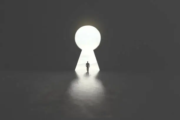 Photo of business man walking under keyhole shaped as a hole in concrete wall