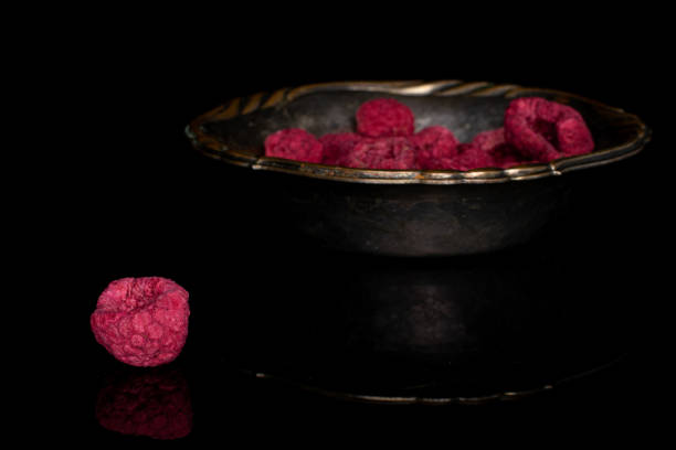 Dried red raspberry isolated on black glass