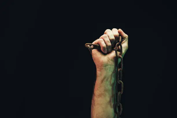 Photo of Human hand are chained in chains isolated on black background.