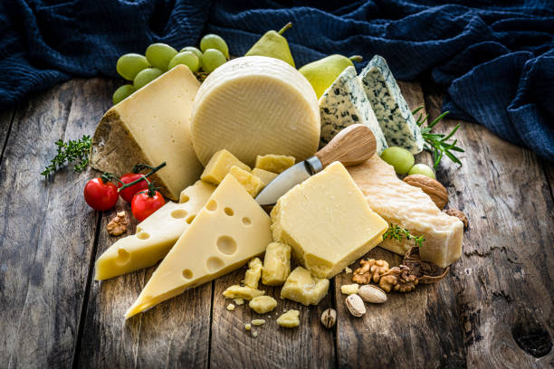 выбор сыров на деревенском деревянном столе - swiss cheese стоковые фото и изображения