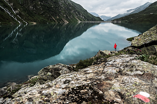 One Single Hiker in a Red Coat Standing at Lake Kartell above St. Anton at the Arlberg in Austria