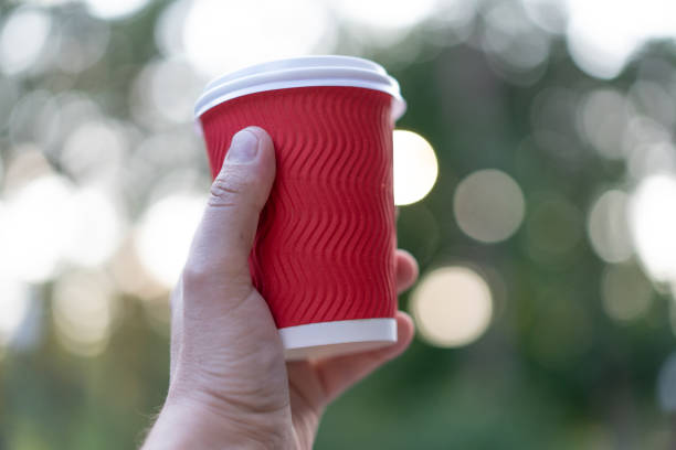 istock Red paper cup for drinks in hand on a background of nature. 1194237286