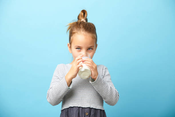 istock Cute five years old girl drinks milk on blue isolated. 1194238146