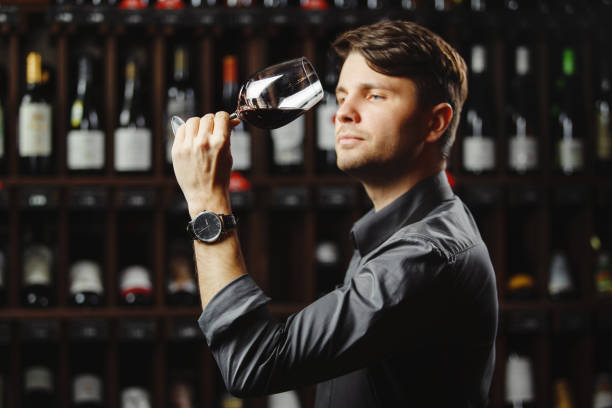 Bokal of red wine on background, male sommelier appreciating drink Bokal of red wine on background of male sommelier appreciating color, quality, flavor and sediments of drink. Professional degustation expert in winemaking. sommelier photos stock pictures, royalty-free photos & images