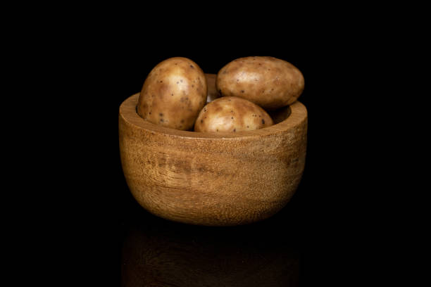Lot of whole tiramisu brown almond nut in bamboo bowl isolated on black glass