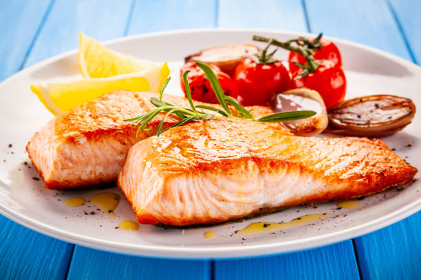 istock Fish dish - fried salmon and vegetables on wooden background 1194242429