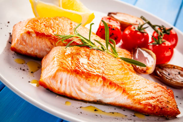 istock Fish dish - fried salmon and vegetables on wooden background 1194242490
