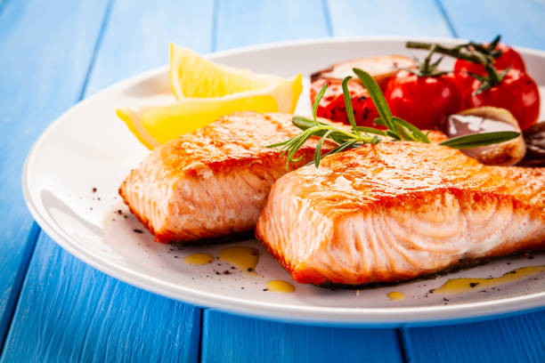 istock Fish dish - fried salmon and vegetables on wooden background 1194242630