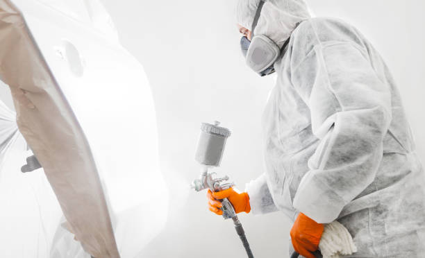 istock Male worker with mask and protective clothes painting car using spray compressor. 1194243273