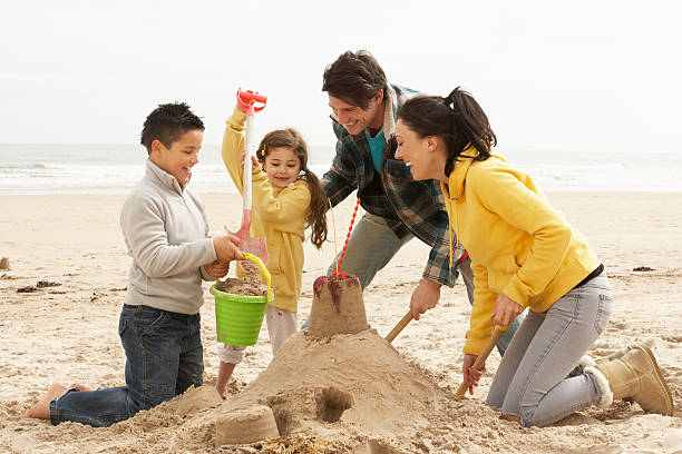 Family Building Sandcastle On Winter Beach stock photo