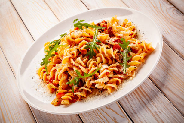 istock Pasta with pork, sauce and vegetables on color gradient background 1194247656