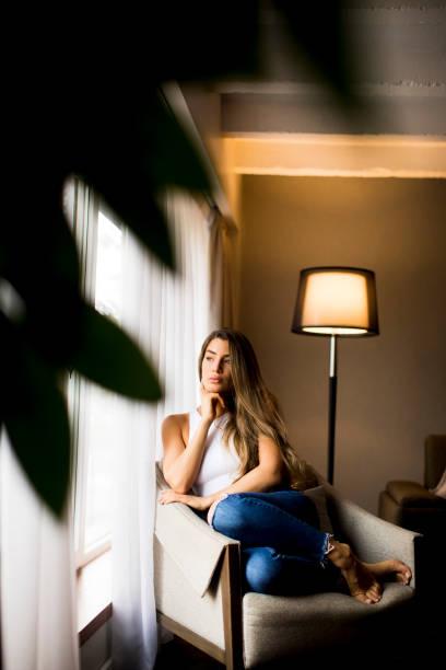 istock Beautiful young woman sitting by the window 1194249620