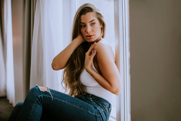 istock Beautiful young woman sitting by the window 1194249633